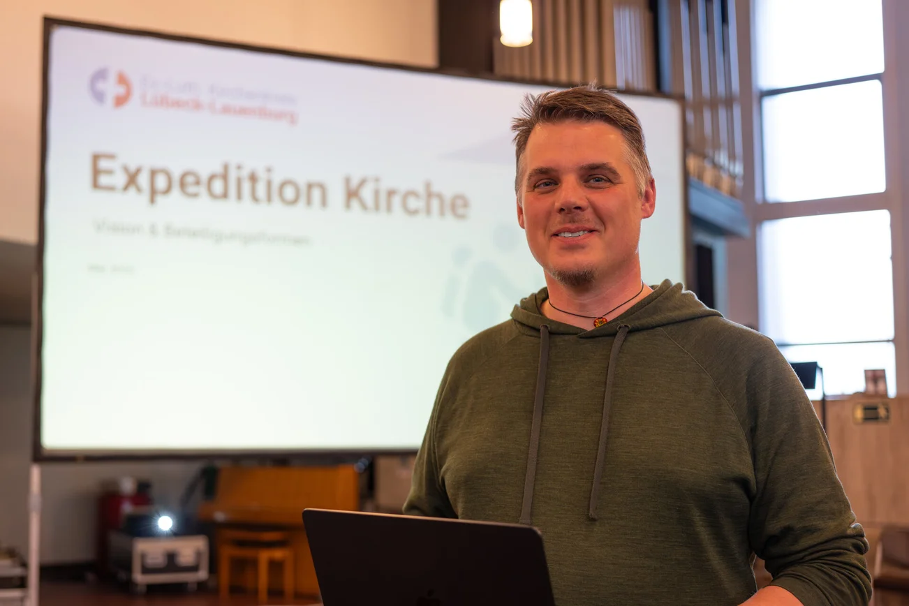 Ein Mann steht vor einer Videowand. 