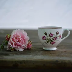 Kaffeetasse, daneben liegt eine Rose