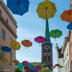 Aufgespannte Regenschirme in verschiedenen Farben, an mehreren Seilen aufgehängt - Im Hintergrund St. Jakobi Lübeck