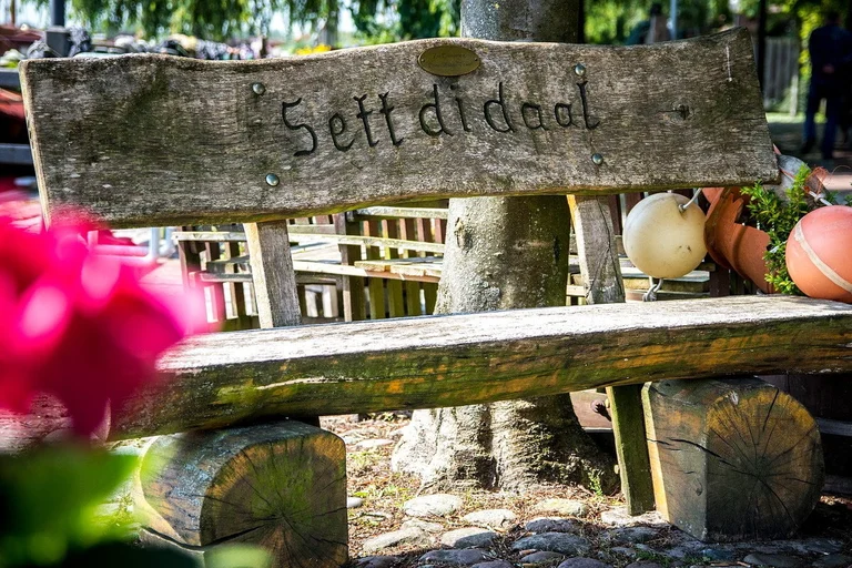 Holzbank mit plattdeutscher Schrift: Sett di daal